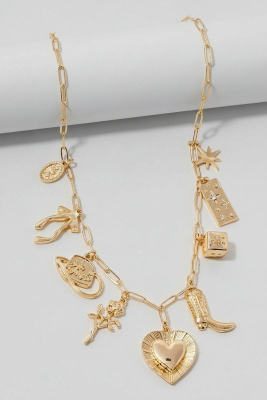 A gold-colored layered statement necklace with crystal accents, featuring various charms including a heart and a boot, displayed against a white background.