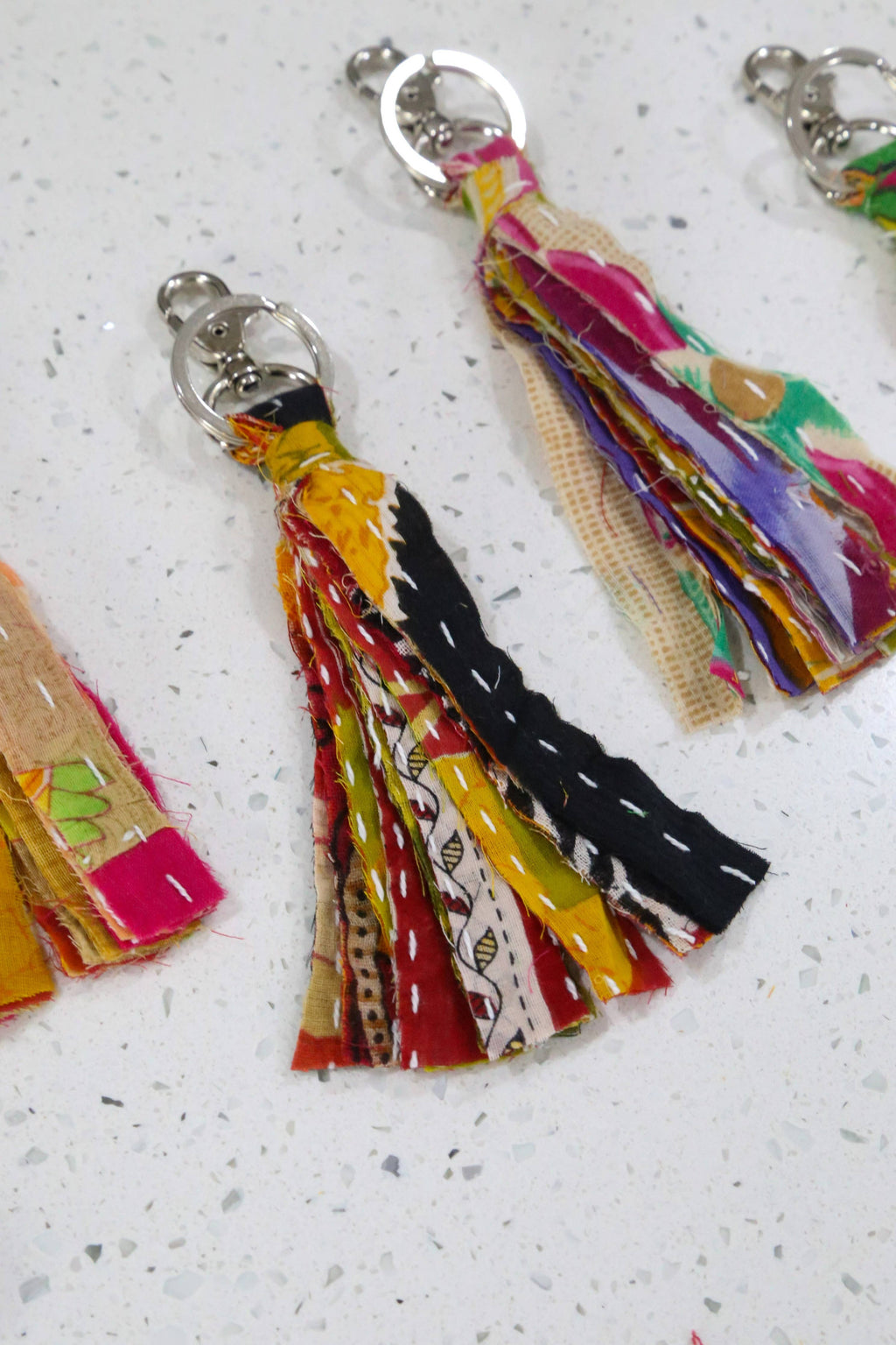 Colorful tassel keychains on a light gray surface