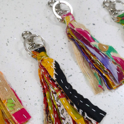 Colorful tassel keychains on a light gray surface