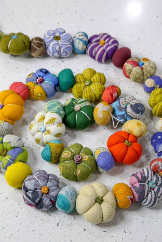 Close-up of mini pumpkin garland featuring vibrant recycled saree beads and handmade fabric pumpkins