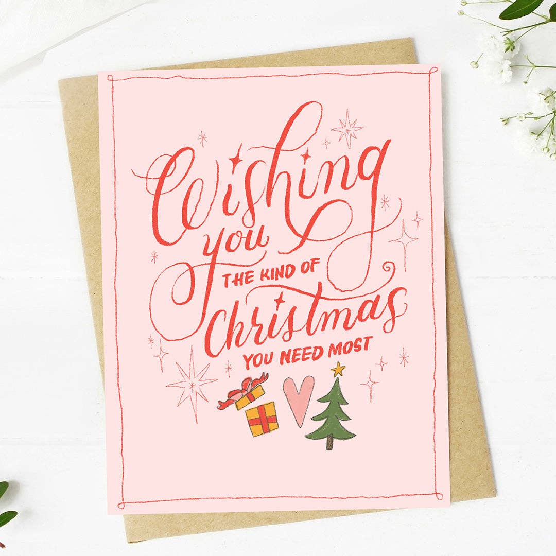 Pink Christmas card with red text and festive illustrations on a white background