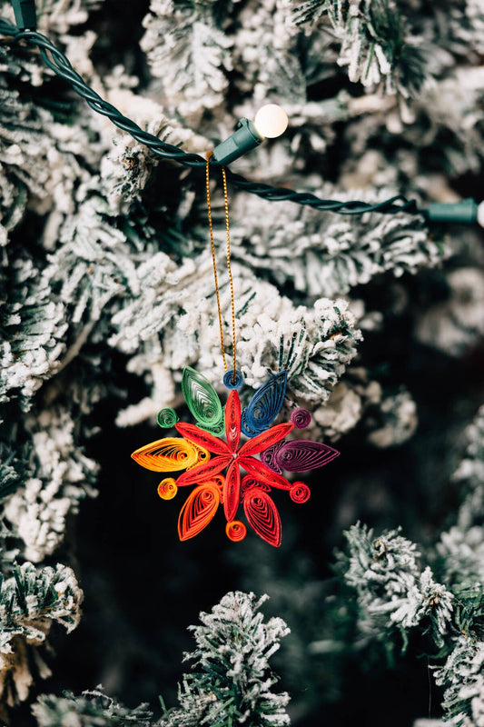 Colorful paper quilled ornament hanging on a frosted Christmas tree