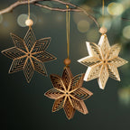 A view of three Nukeela Paper Star ornaments in three neutral holiday colors with a holiday background