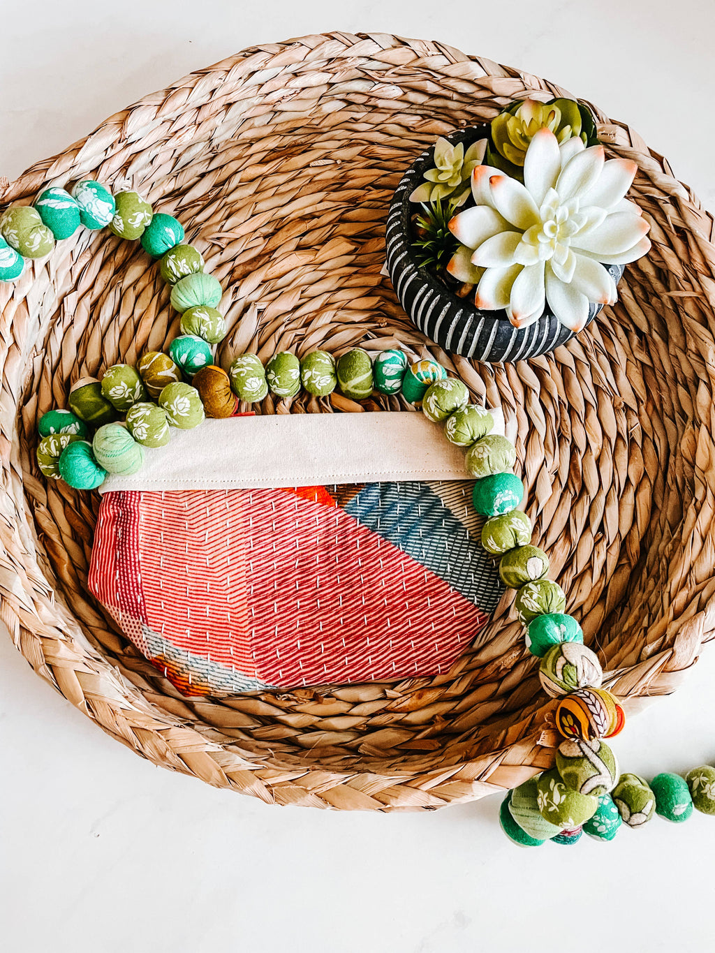 Decorative wreath with beads and succulent on a woven mat showcasing one of the bags
