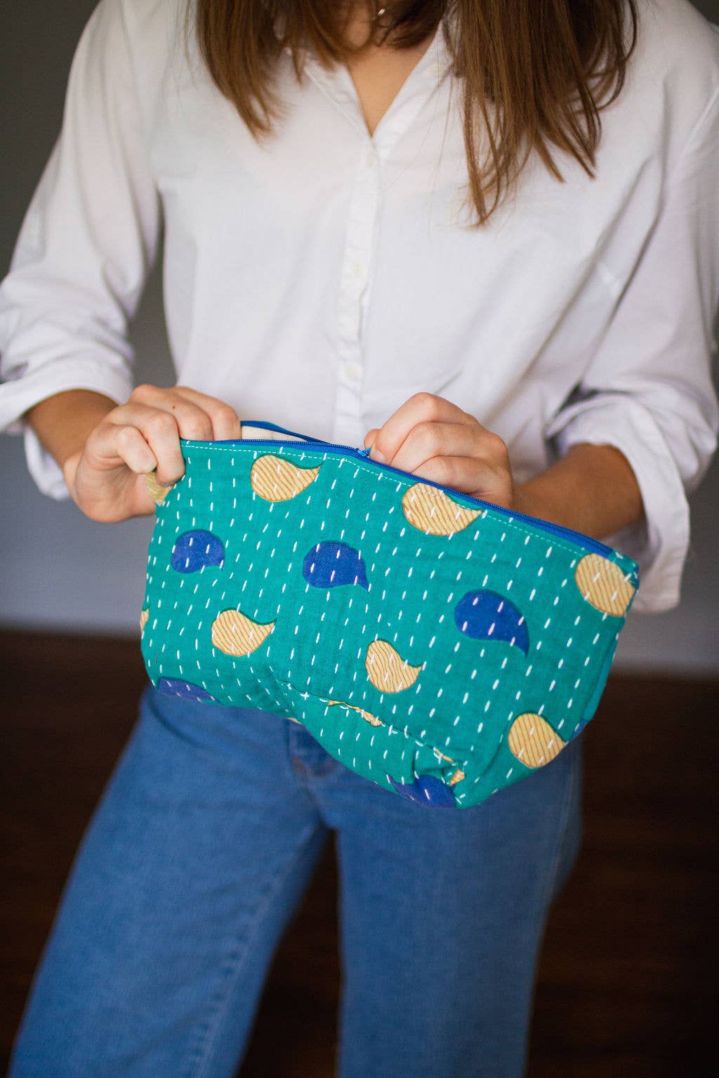 Person holding a blue pouch with yellow and blue patterns