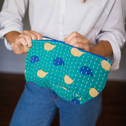 Person holding a blue pouch with yellow and blue patterns