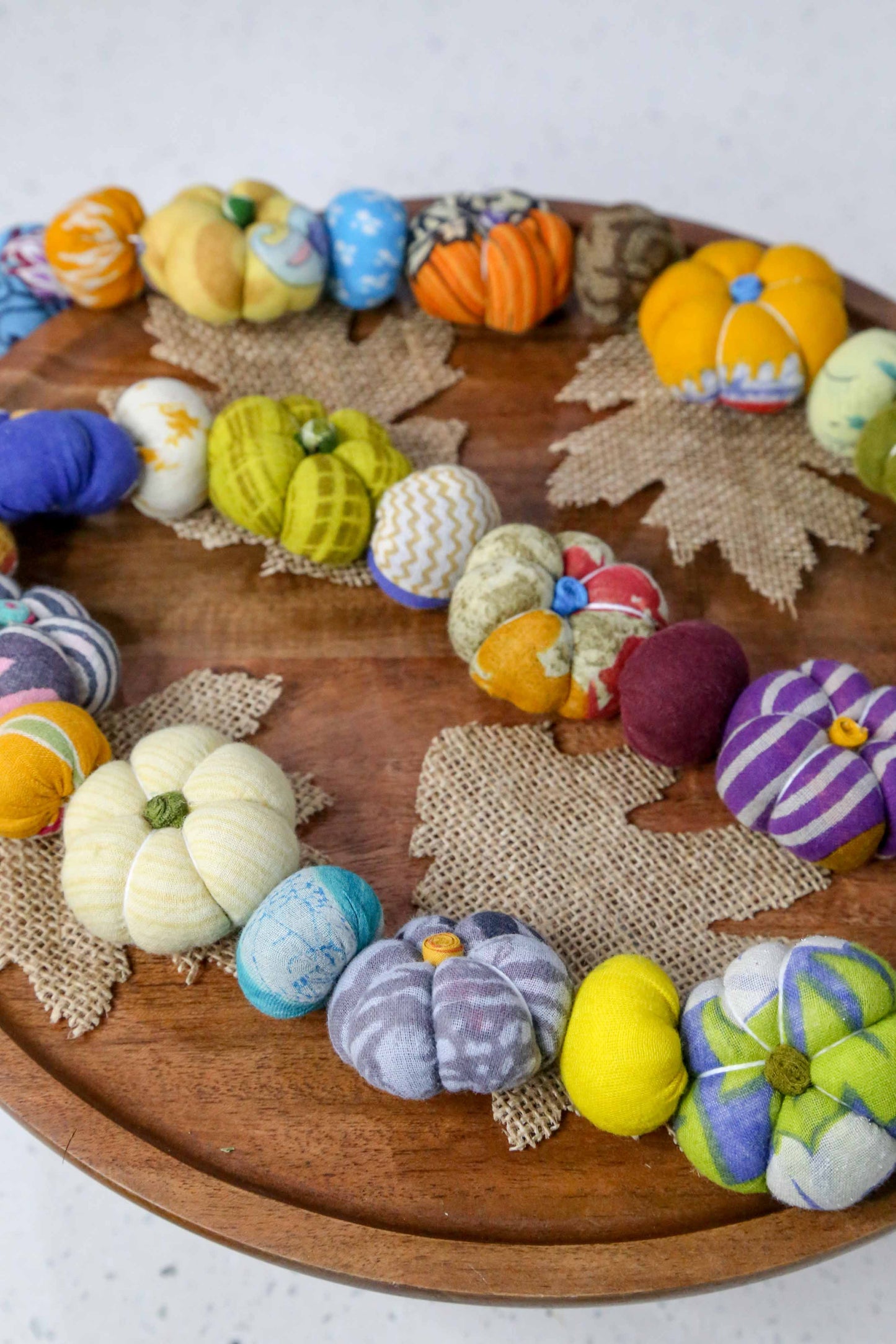Colorful felt pumpkins and leaves on a wooden board with a white background