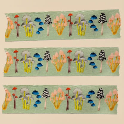 Three strips of fabric with colorful forest pattern on a green background