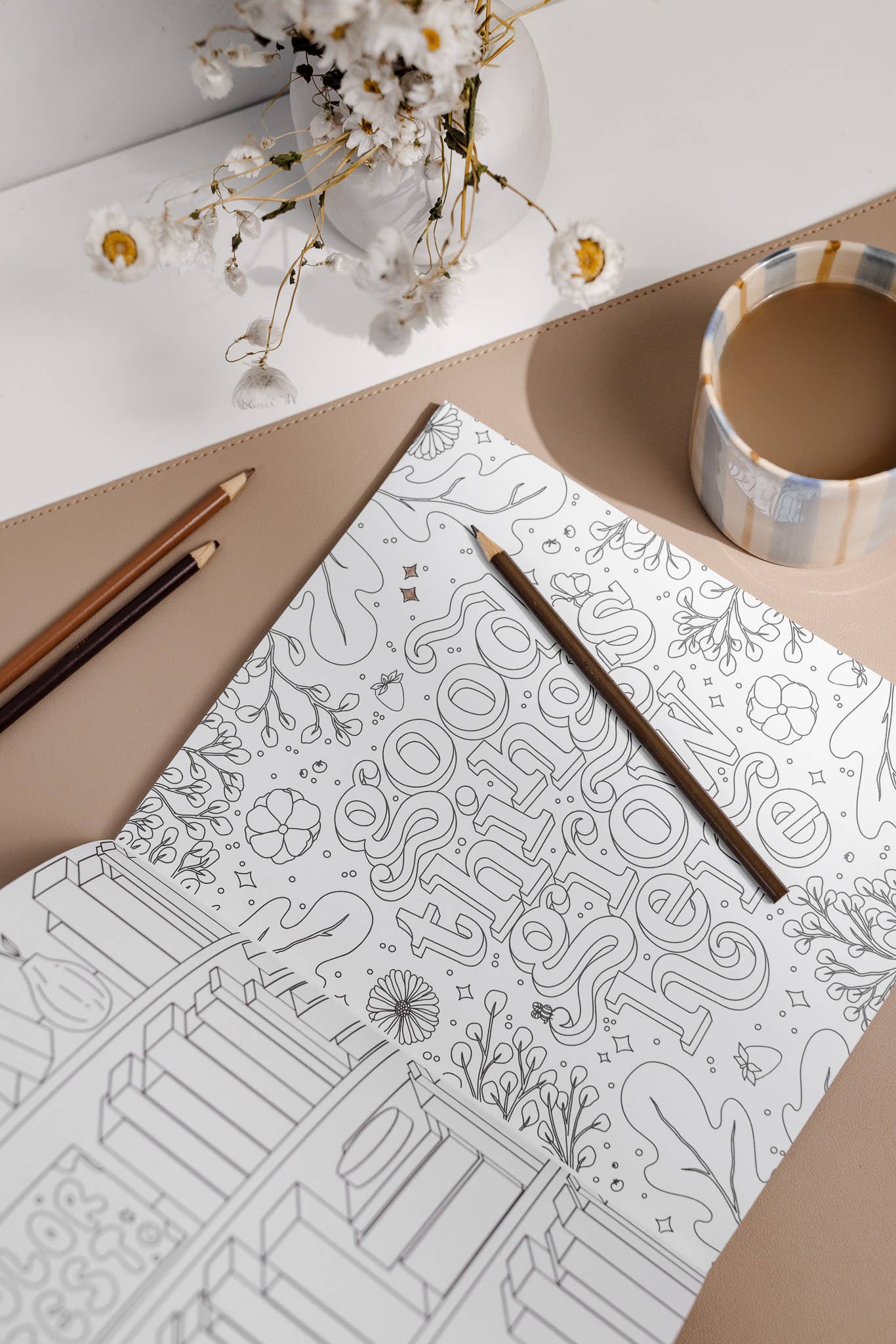 Coloring book with intricate patterns, a pencil, and a cup of coffee on a table.