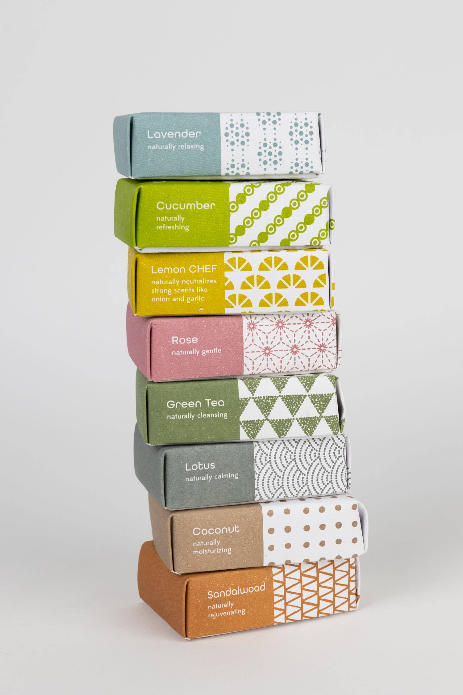 Stack of soap boxes with various scents on a light gray background