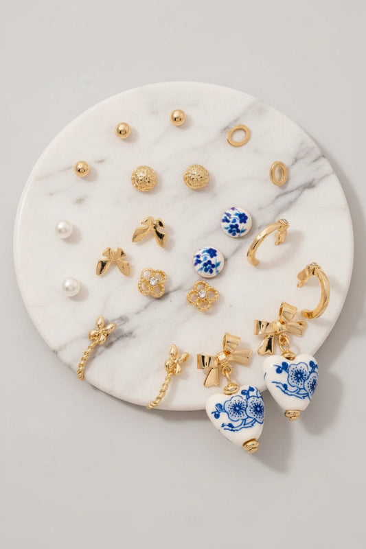A collection of ceramic earrings with pearl and ribbon bow designs displayed on a round white surface.