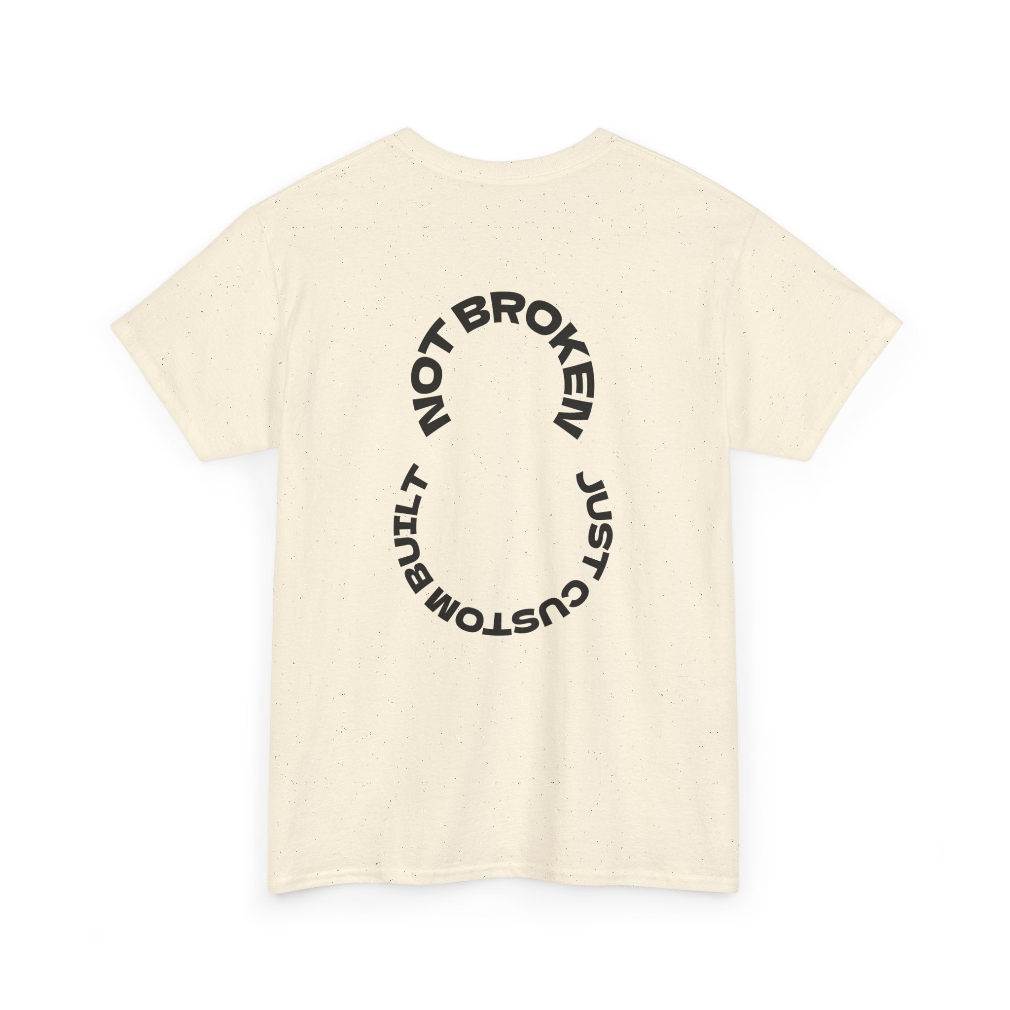 Beige t-shirt with black circular text that says, "Not Broken, Just Custom Built" design on a white background