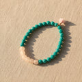 Beaded bracelet with turquoise and beige beads on a light beige background