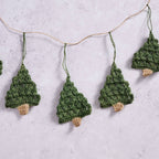 Close up view of the Holly Jolly Trees Crochet Garland on a marble background