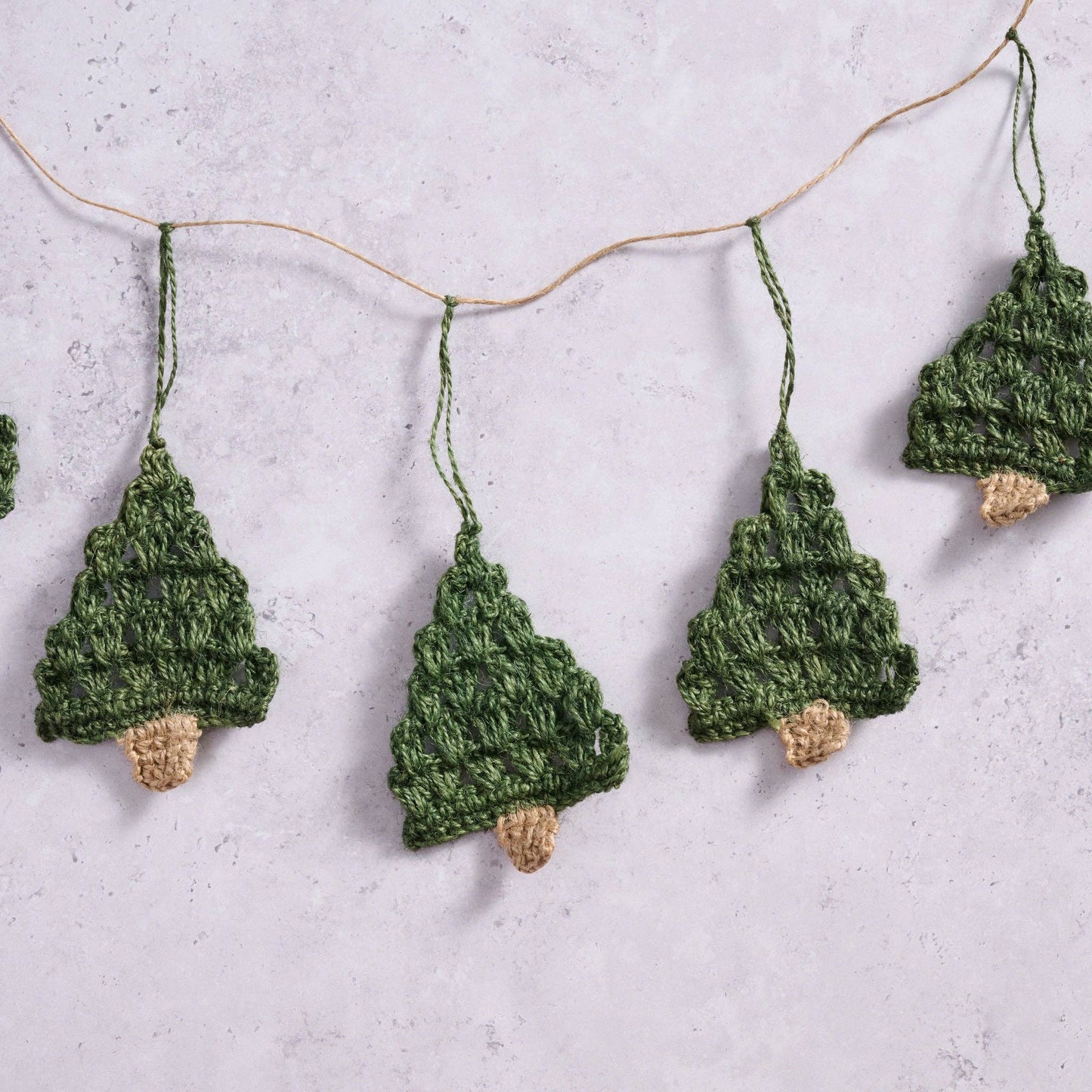 Close up view of the Holly Jolly Trees Crochet Garland on a marble background