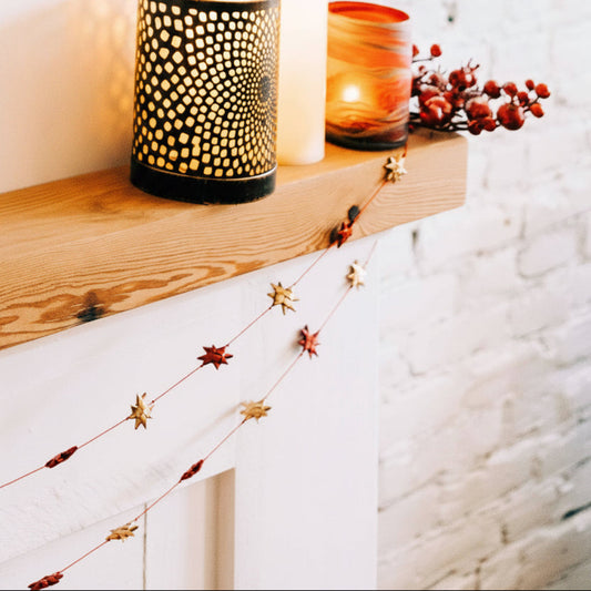 Decorative mantel with candles, a holiday fairy figurine, and festive decorations on a white background