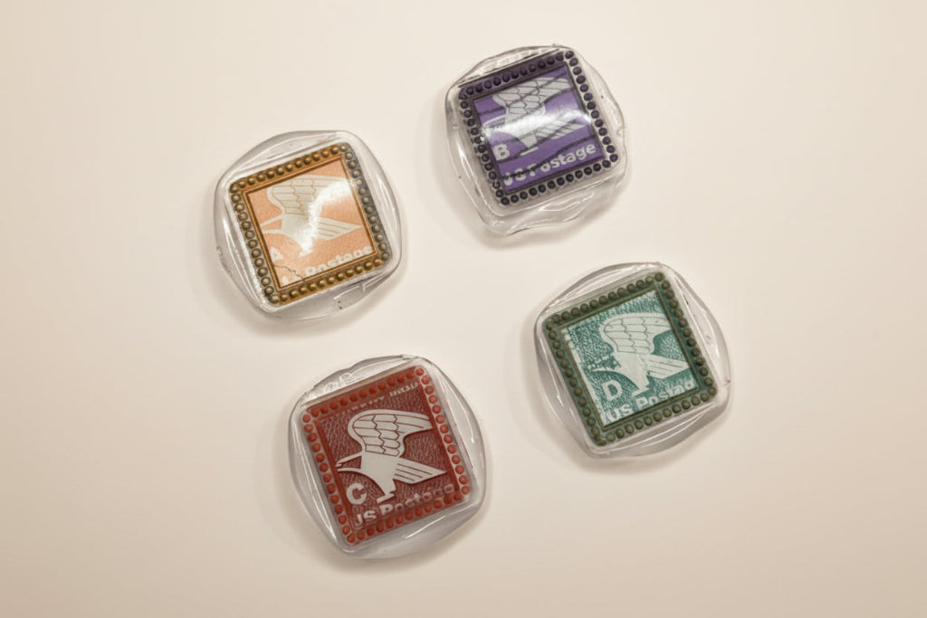 Four vintage-style postage stamp wax magnets created by Rochambeau Home on a white background