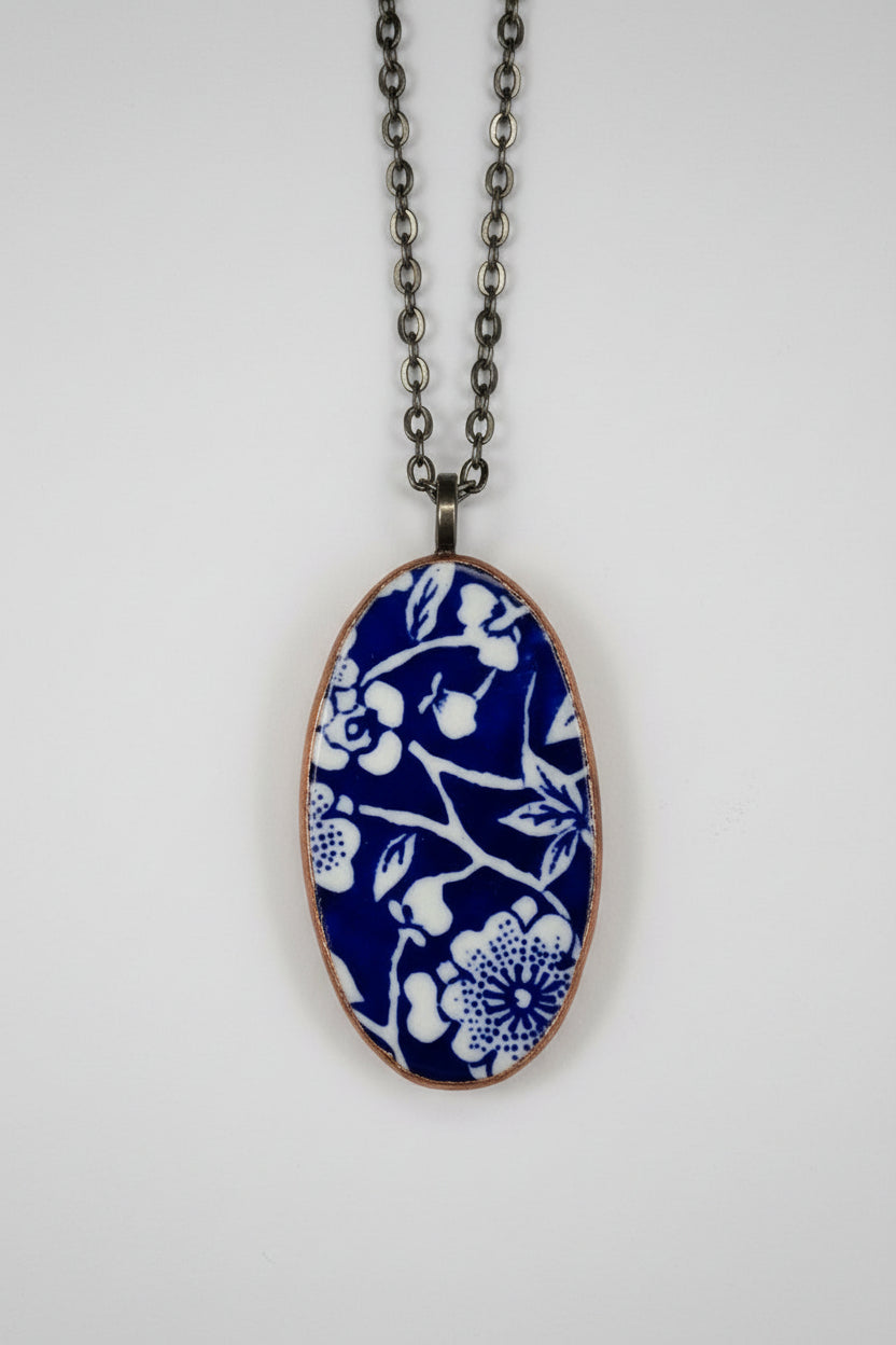 Necklace with a blue and white floral pendant on a light gray background