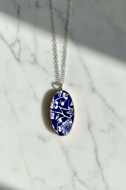 Necklace with a blue floral pendant on a light gray background
