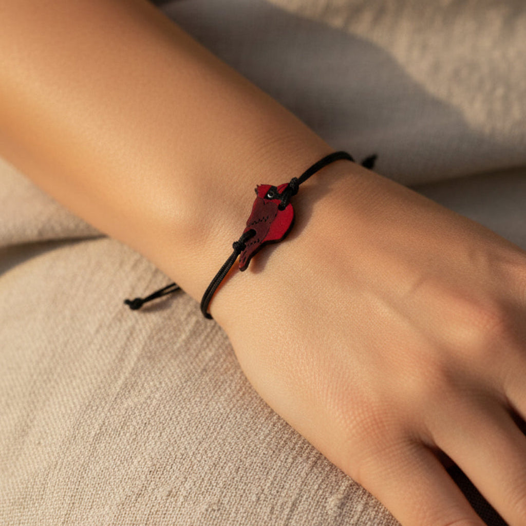 A bracelet with a cardinal bird pendant on a white background