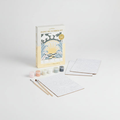 Celestial paint-by-number kit with packaging, canvases, paint, and brushes on a white background