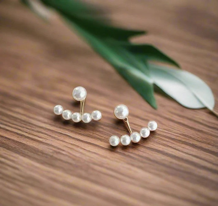 Close-up of pearl huggie earrings on a neutral background