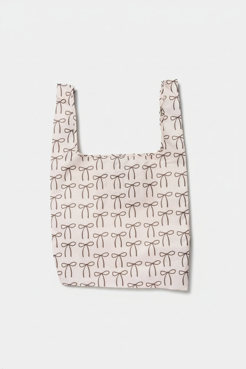 A cream-colored foldable tote adorned with brown bows, made from high-quality ripstop nylon for durable everyday use.