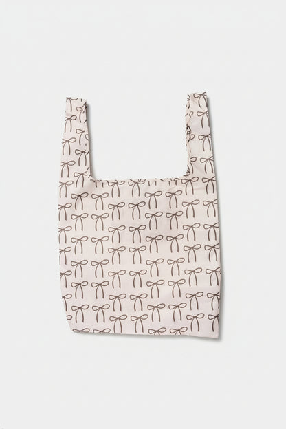 A cream-colored foldable tote adorned with brown bows, made from high-quality ripstop nylon for durable everyday use.