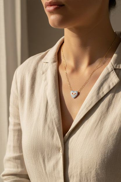 Necklace with a heart-shaped pendant being worn on a person against a neutral background and beige garment