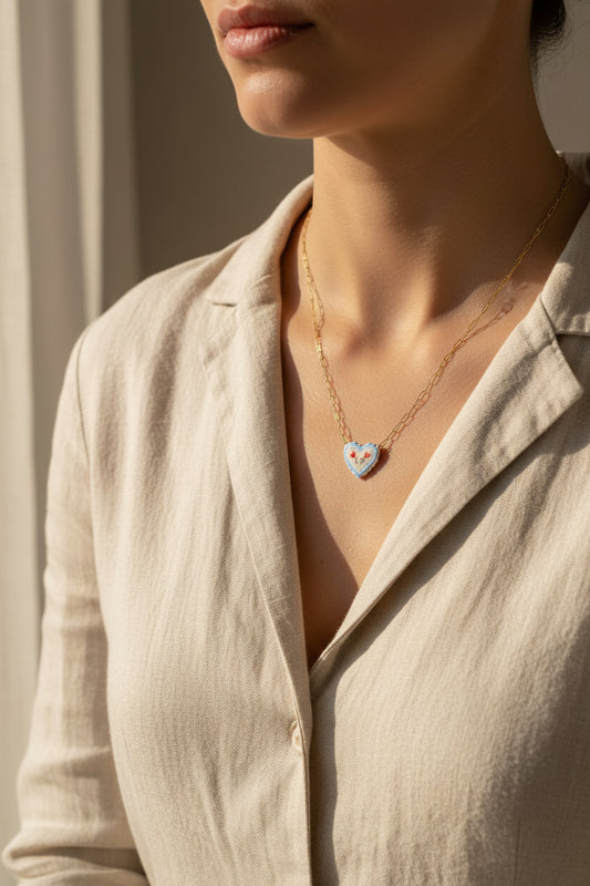 Necklace with a heart-shaped pendant being worn on a person against a neutral background and beige garment