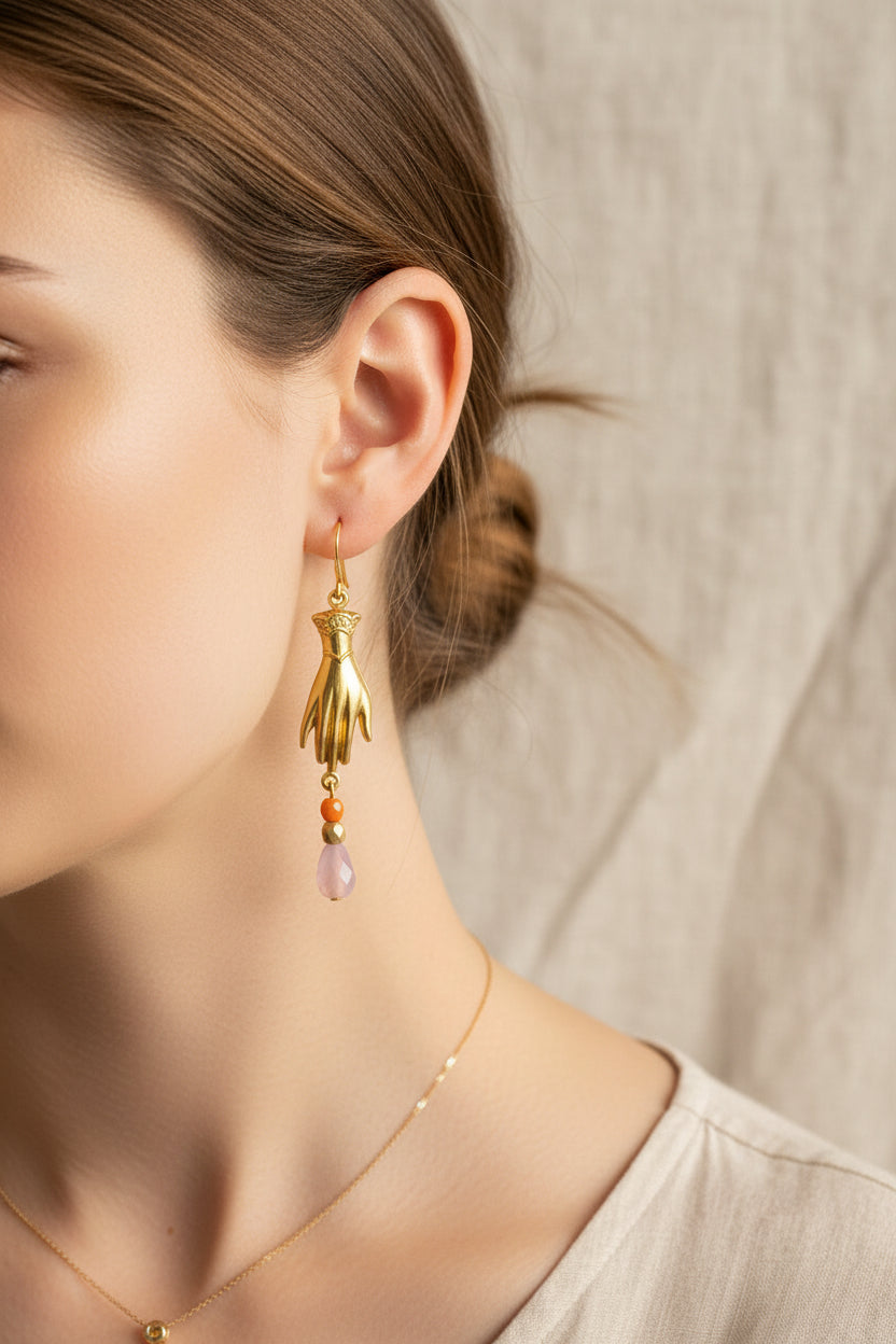 Gold hand-shaped earrings with colorful beads on a light gray background