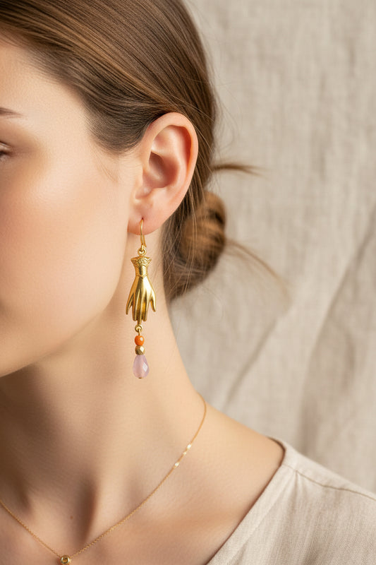 Gold hand-shaped earrings with colorful beads on a light gray background