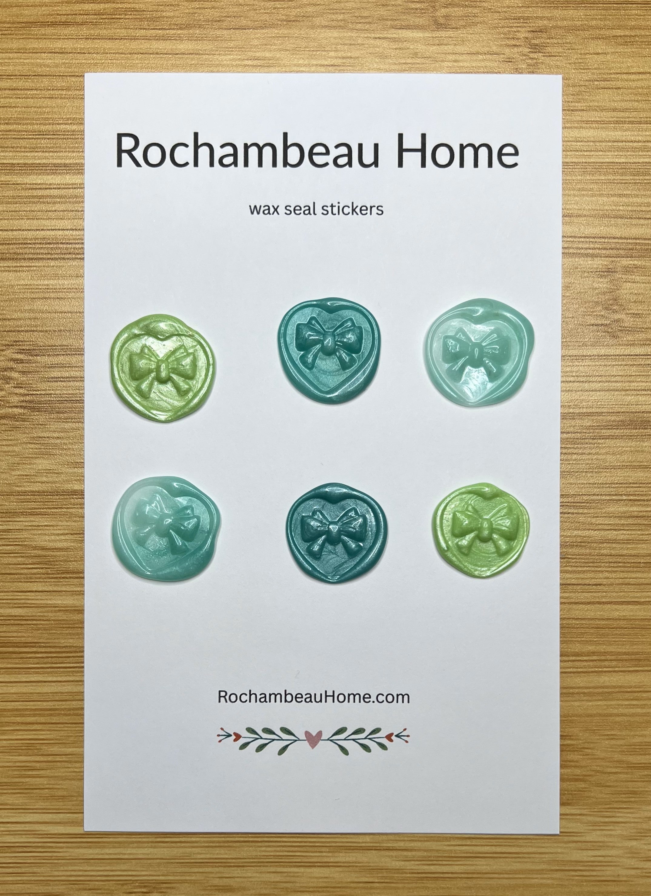 Close up view of the Heart & Bow wax seal stickers in a green hue