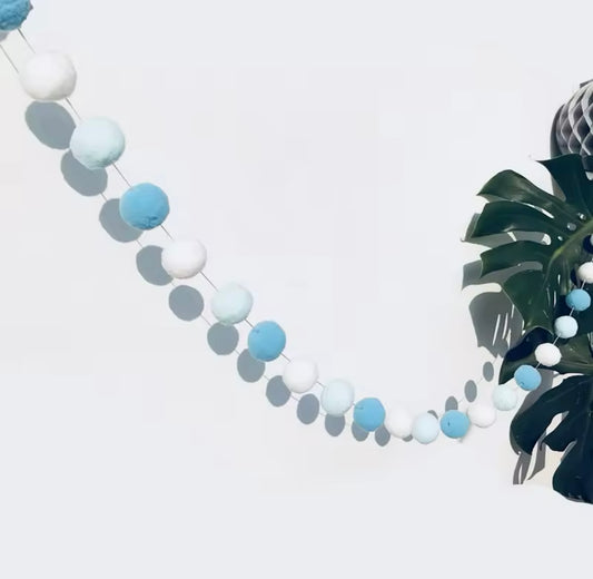 Close-up of blue and white felt ball garland on wall