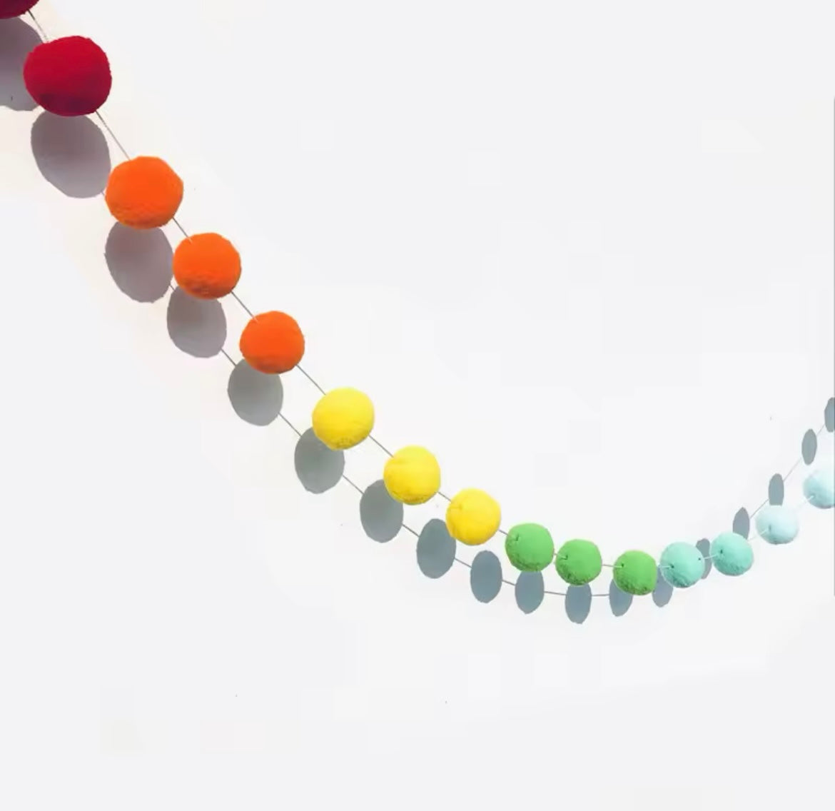 Close-up of vibrant rainbow wool felt balls on string