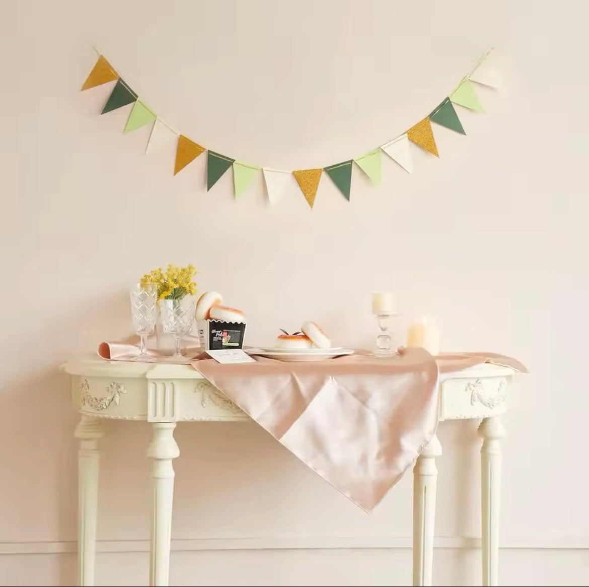 Green, gold glitter, and cream triangle banner hanging across a party space