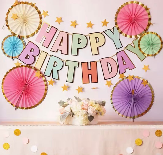 Pastel HAPPY BIRTHDAY banner with gold outline hanging at a party
