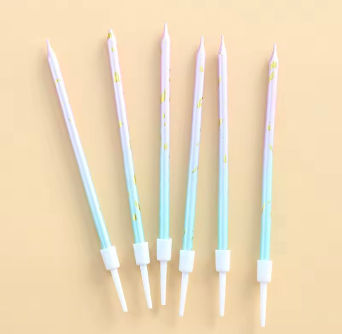 Long pastel candles with gold accents arranged next to mermaid-themed decor