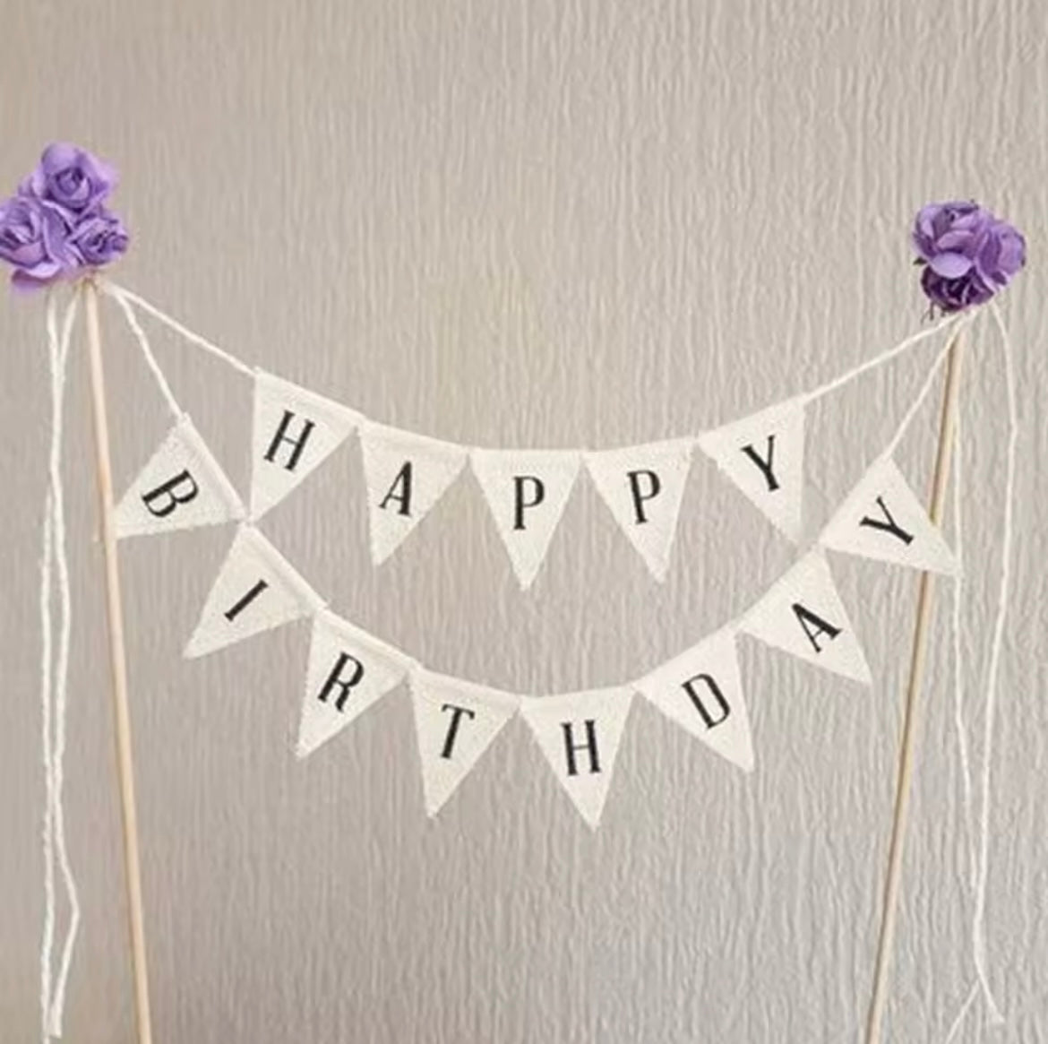 Wooden stake birthday flag among floral frosting