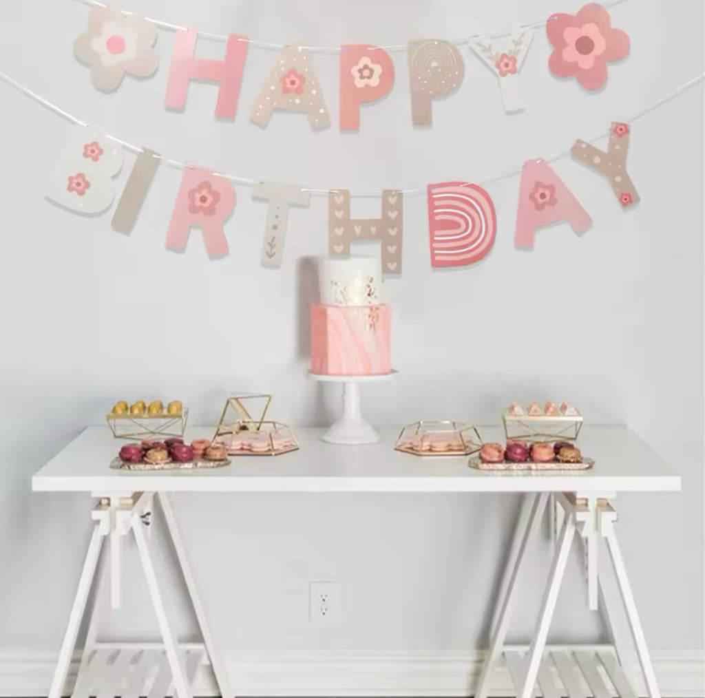 Pink floral birthday banner with rainbow and star details hangs over a birthday display