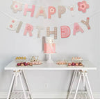 Pink floral birthday banner with rainbow and star details hangs over a birthday display