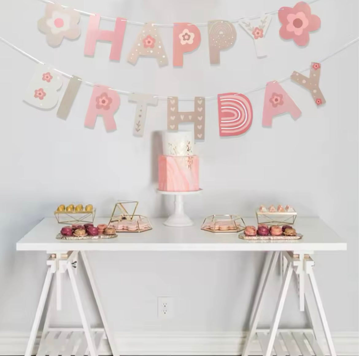 Pink floral birthday banner with rainbow and star details hangs over a birthday display