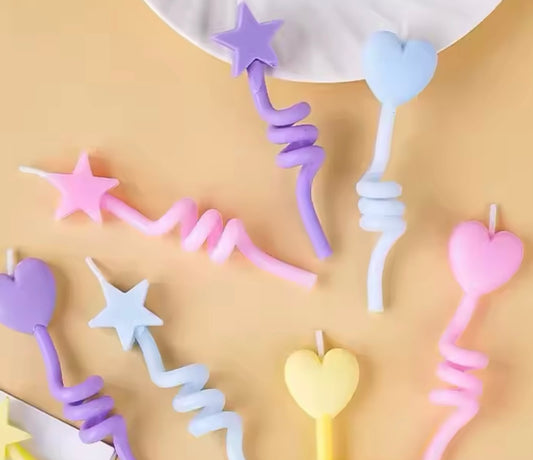 Close-up of ombré star-topped candles in pink, blue, yellow, and purple