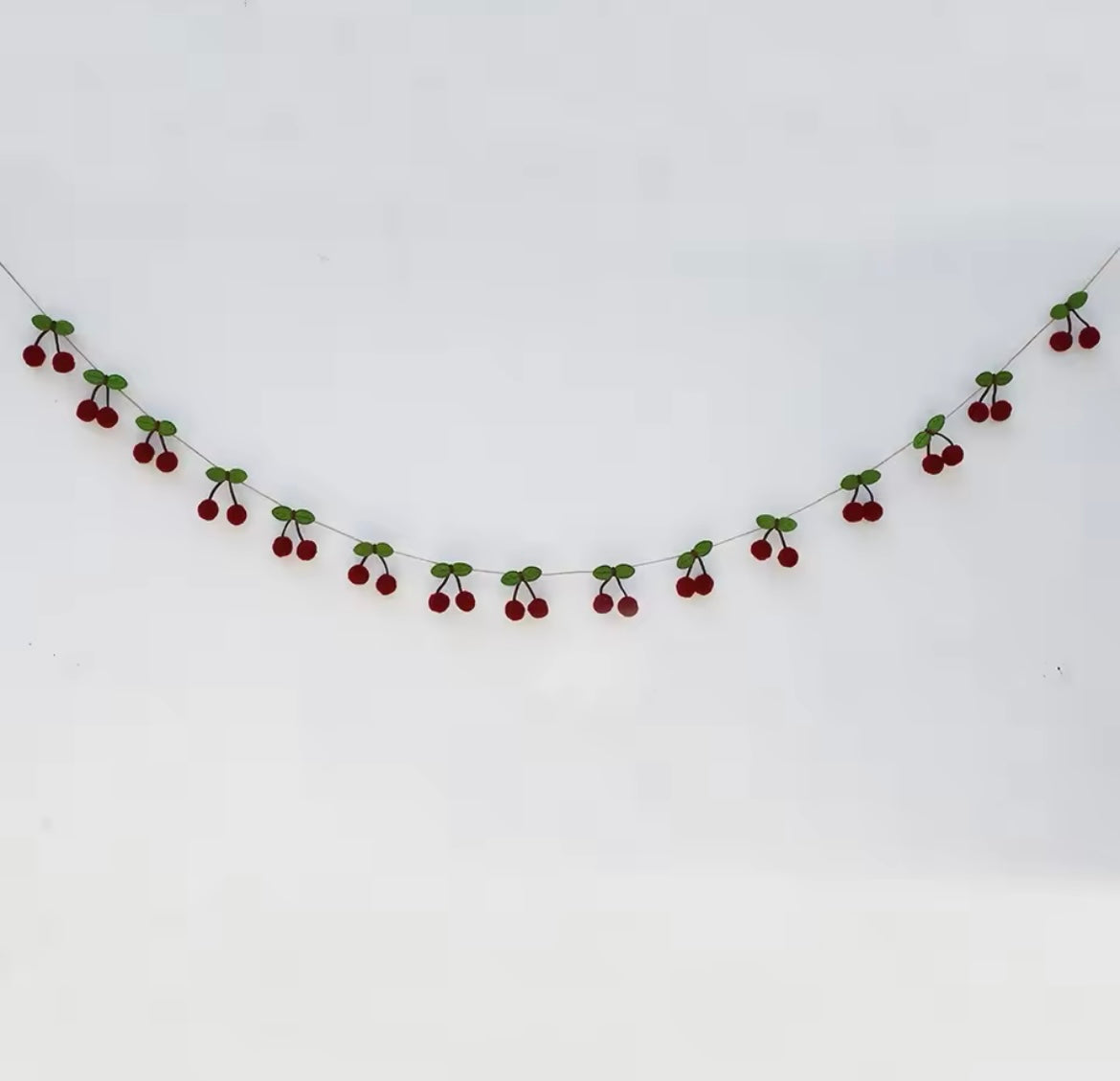 Red cherry felt banner hanging across a white wall for a summer party