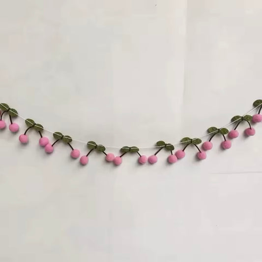 Pink cherry felt banner styled on a white wall for a summer party