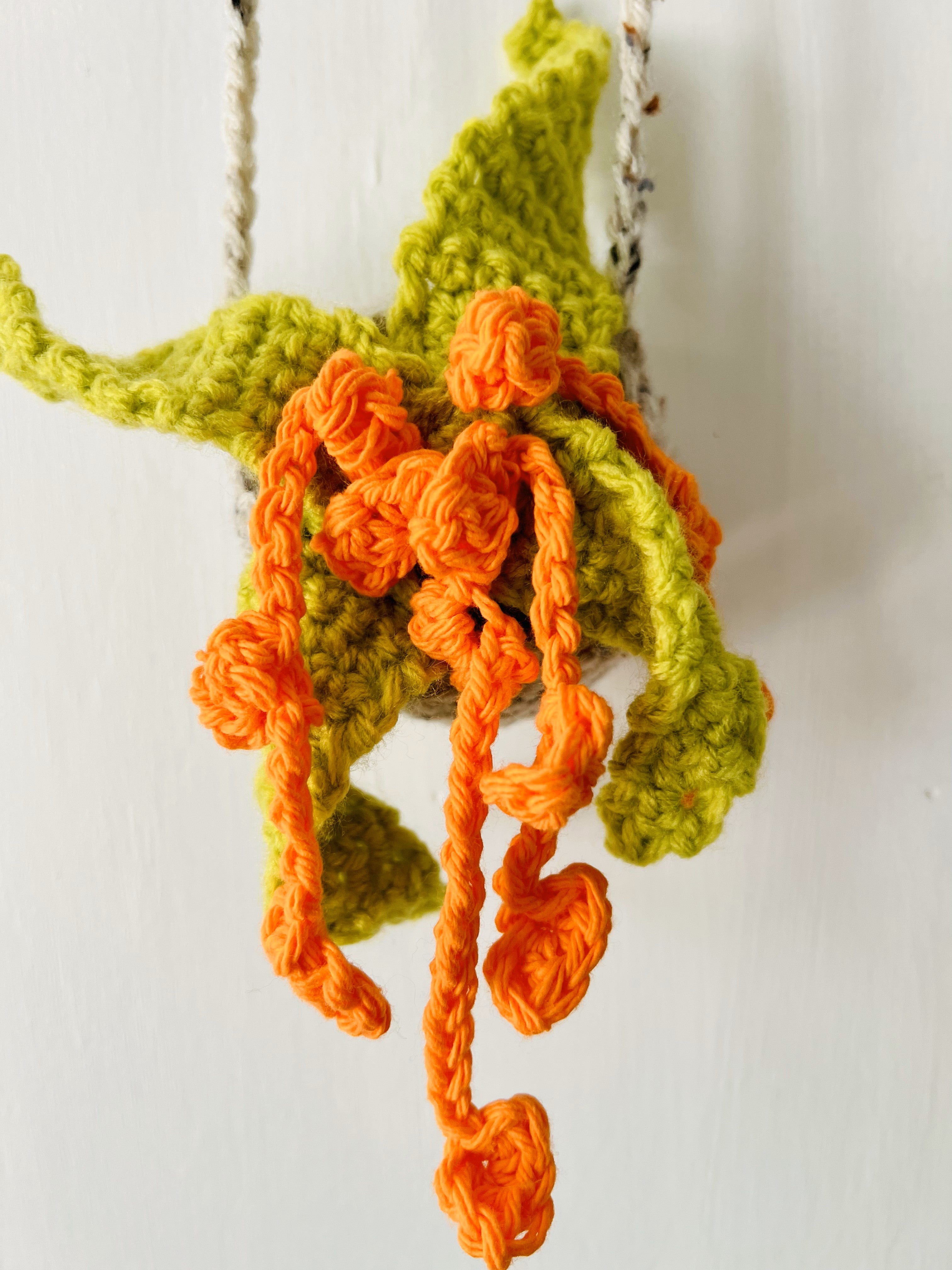 Close-up of textured yarn leaves and floral details on crocheted plant