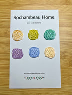 Close up view of the Cozy Quilted Flower wax seal stickers in a variety of colors on a 6 pack card