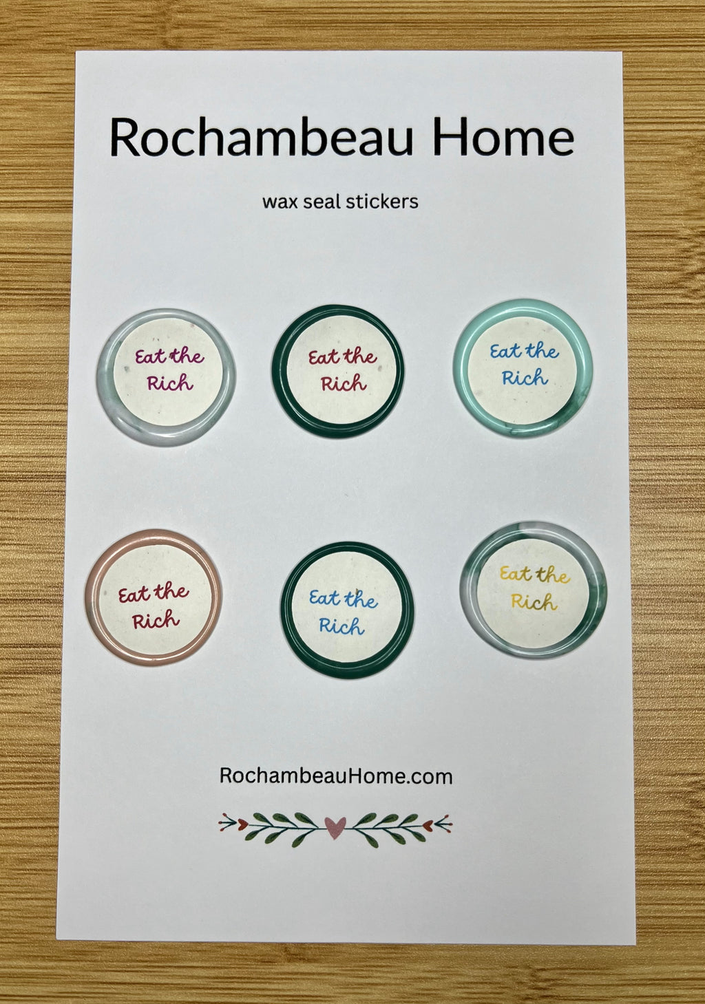 Close up view of the Eat the Rich wax seal stickers on a 6 pack card