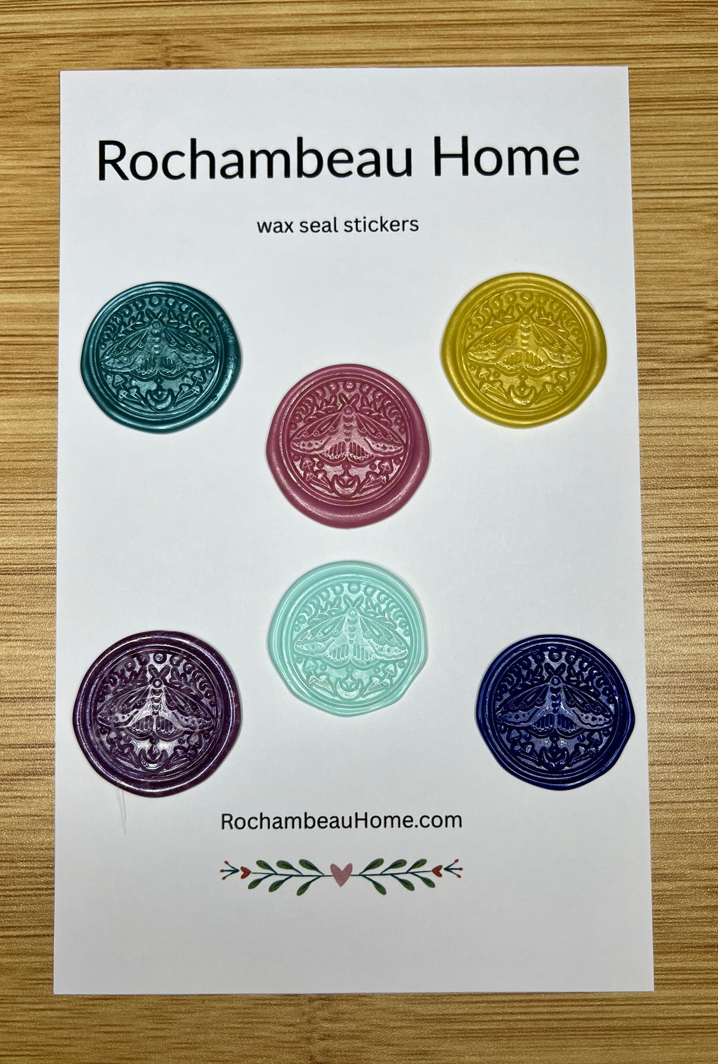 Close up view of the Lunar Moth boho wax seal stickers in a variety of colors on a paper card