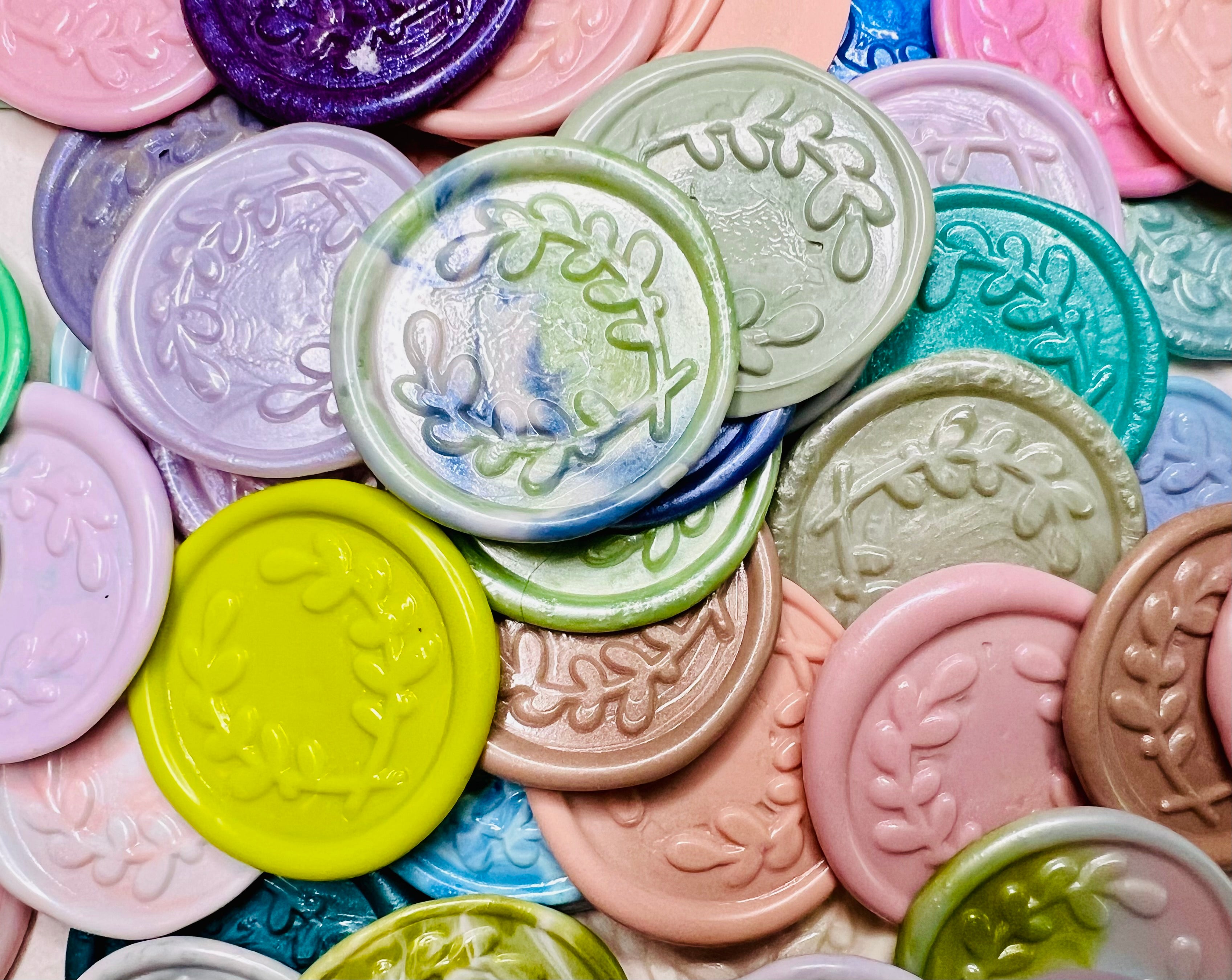 A close up view of the Olive You Always wax seal stickers in a mixture of solid and rainbow multicolor